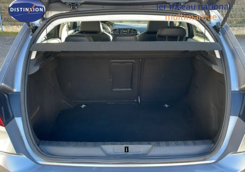 Coffre ouvert d’une Peugeot 308 gris Artense métal, vue arrière montrant l’espace de chargement vide et la banquette arrière.