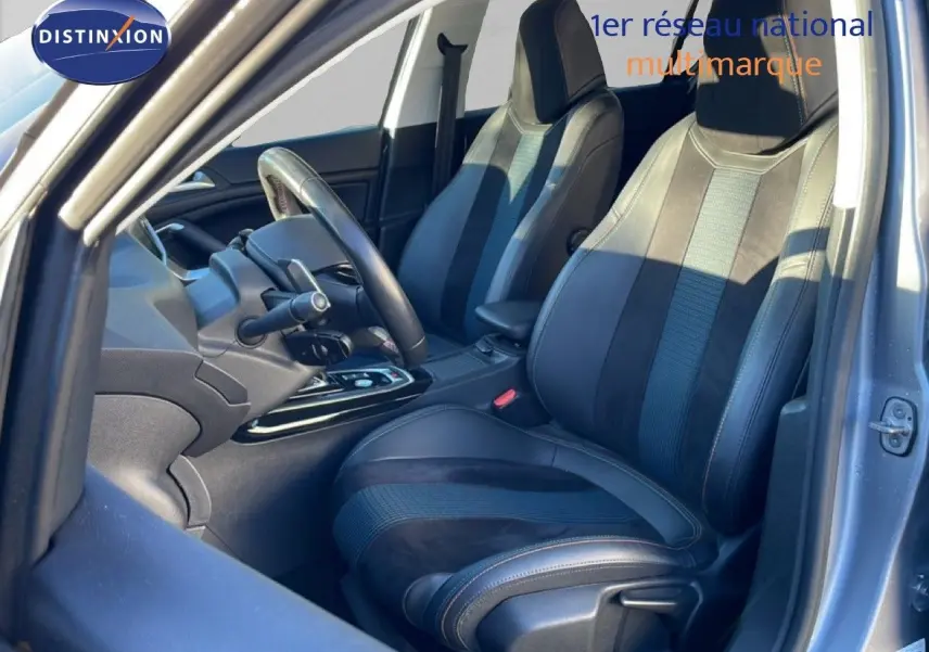 Vue intérieure côté conducteur de la Peugeot 308 gris Artense, mettant en valeur les sièges en cuir noir et alcantara.