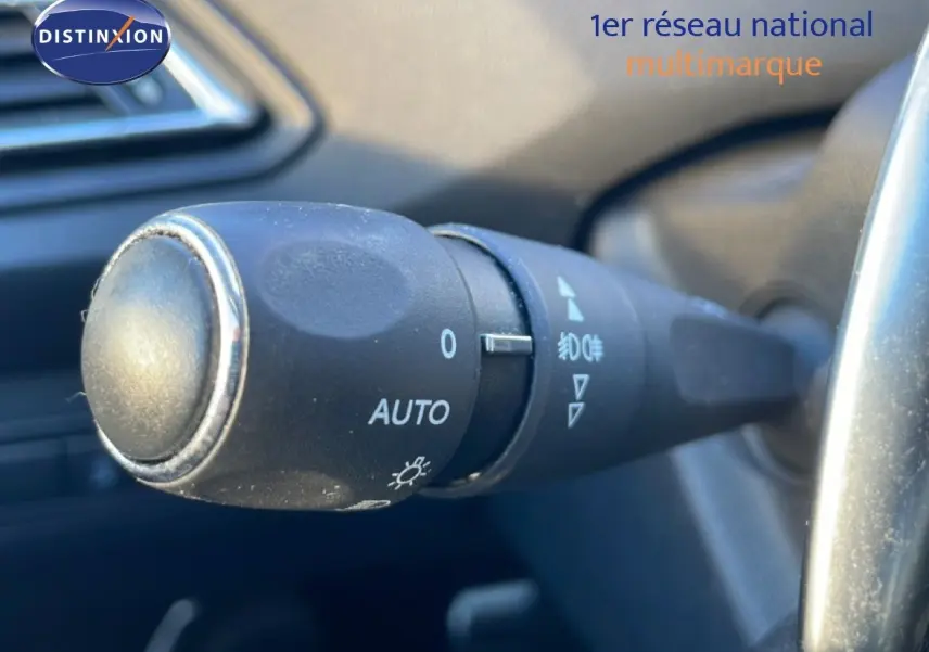 Gros plan sur la commande des phares en mode automatique à l'intérieur d'une Peugeot 308 gris Artense de 2019.