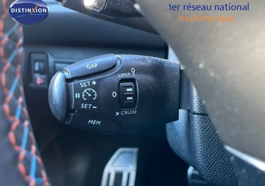 Gros plan sur la commande de régulateur de vitesse au volant d’une Peugeot 308 gris Artense, intérieur cuir noir.