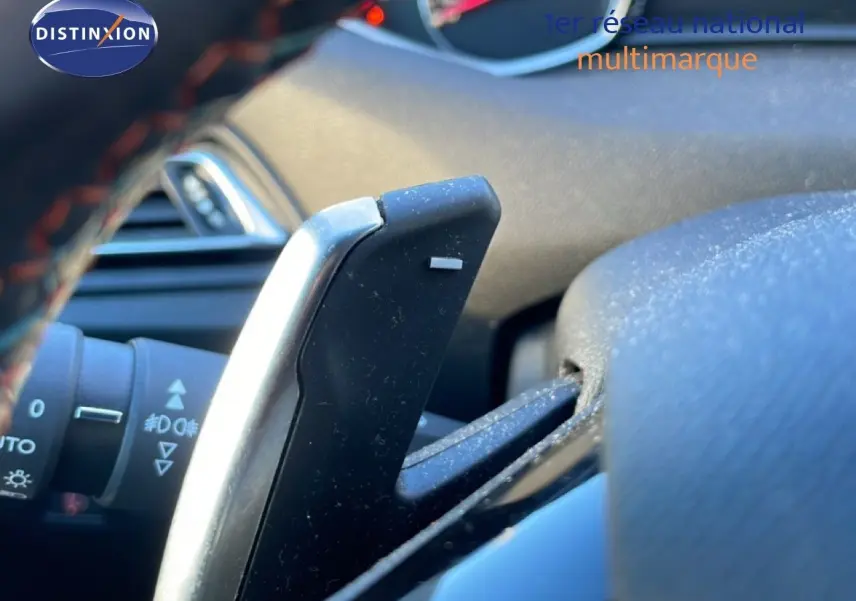 Gros plan sur la palette de changement de vitesse côté droit du volant d’une Peugeot 308 gris Artense, intérieur visible.