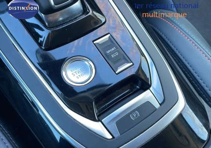 Gros plan sur la console centrale noire brillante de la Peugeot 308 gris Artense, avec bouton start/stop et sélecteur modes sport/eco.