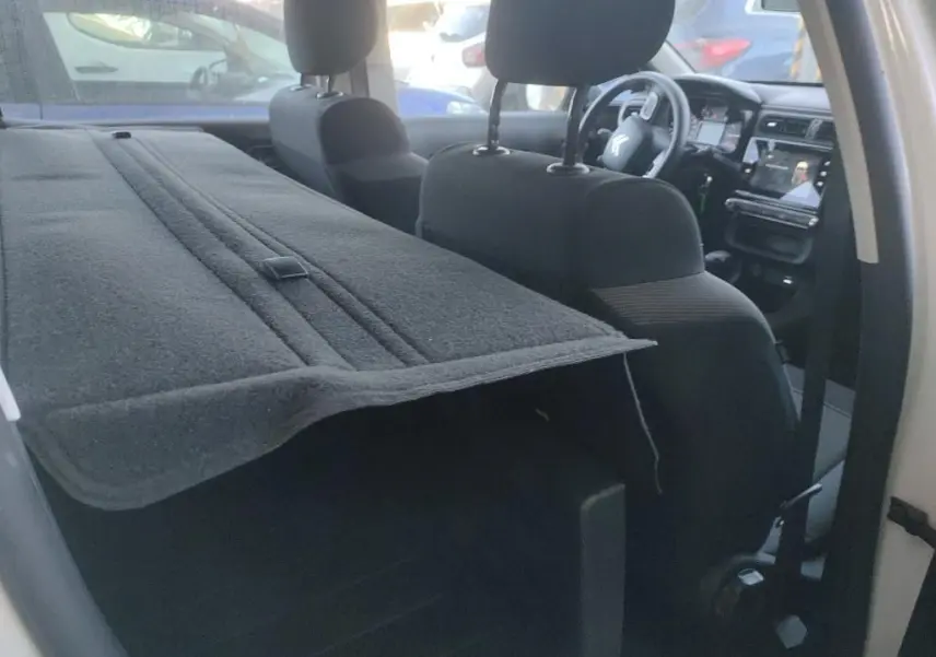 Vue intérieure côté droit d'une Citroën C3 Société blanche, montrant les sièges avant et la tablette arrière déployée.