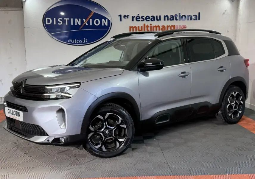 Citroën C5 Aircross gris clair en 3/4 avant droit, avec jantes noires et toit noir contrasté en intérieur showroom.