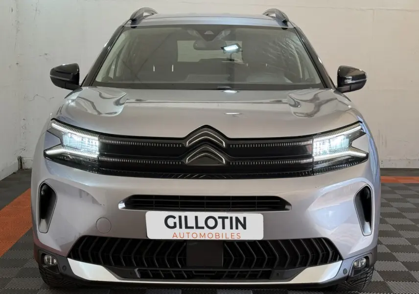 Vue frontale d'un Citroën C5 Aircross gris clair avec phares LED allumés et calandre noire distinctive.