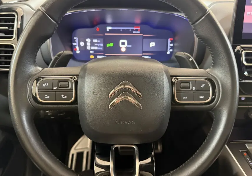 Vue rapprochée du volant cuir multifonctions de la Citroën C5 Aircross 2023 avec tableau de bord numérique lumineux.
