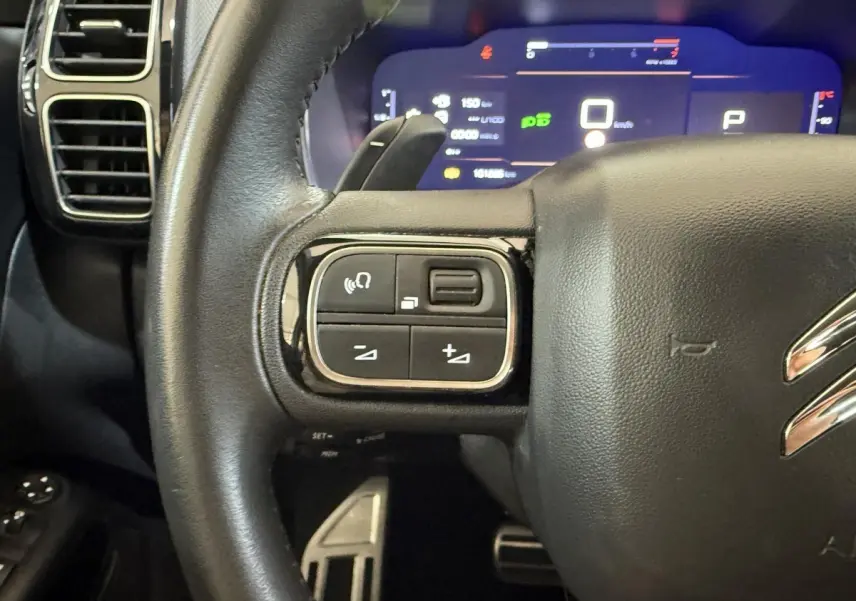 Gros plan sur le volant cuir noir côté gauche du Citroën C5 Aircross 2023 avec commandes intégrées et tableau de bord numérique.