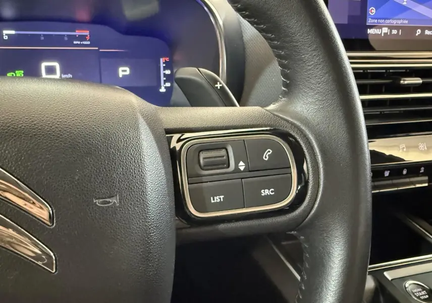 Gros plan sur le volant cuir noir côté droit du Citroën C5 Aircross 2023 avec commandes audio et tableau de bord numérique.