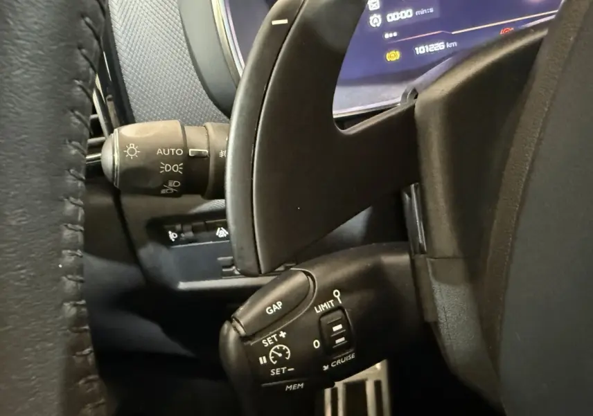 Gros plan sur la commande de régulateur de vitesse et les palettes au volant d’un Citroën C5 Aircross gris clair, intérieur noir.