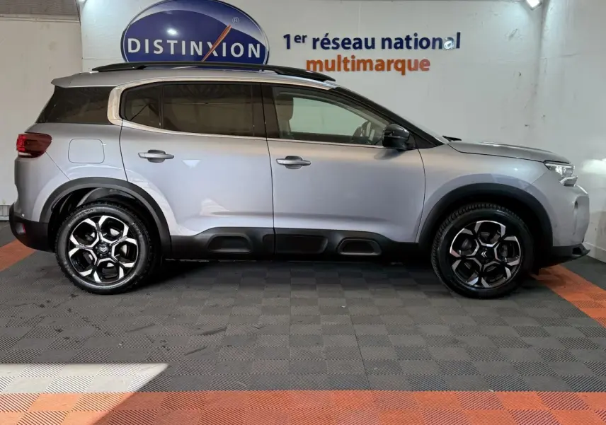 Vue de profil côté droit d'un Citroën C5 Aircross gris clair avec jantes noires et protections noires basses.
