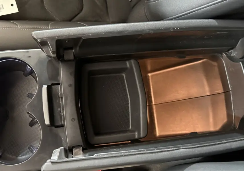 Vue intérieure en plongée du rangement central ouvert du Citroën C5 Aircross gris clair, montrant le compartiment de console entre les sièges.