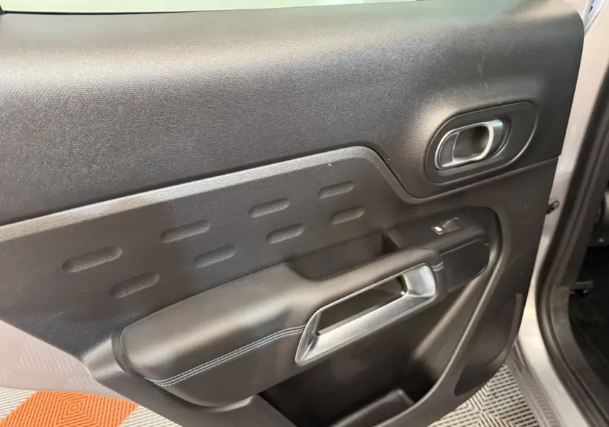 Vue rapprochée de la porte avant droite du Citroën C5 Aircross gris clair, avec poignée argentée et surpiqûres bleues.
