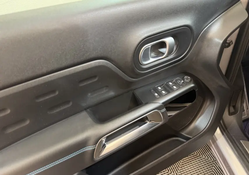 Gros plan sur la porte avant droite noire du Citroën C5 Aircross 2023 avec commandes de vitres et poignée chromée.