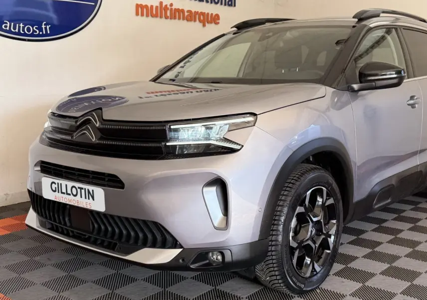 Vue 3/4 avant droit du Citroën C5 Aircross gris clair avec calandre noire et jantes noires brillantes.