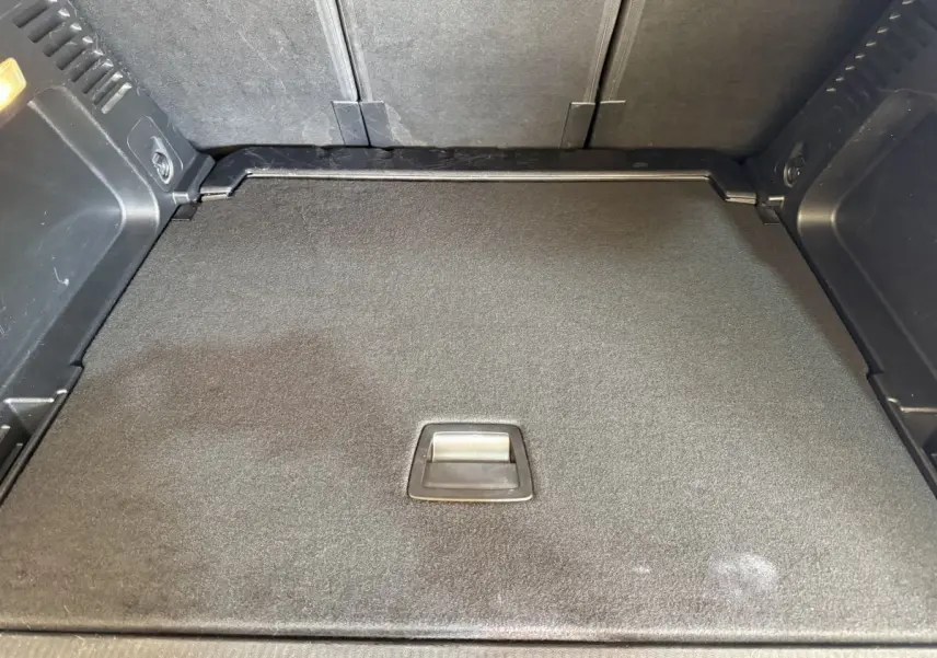 Vue rapprochée du coffre gris clair du Citroën C5 Aircross 2023 avec plancher plat et poignée centrale intégrée.