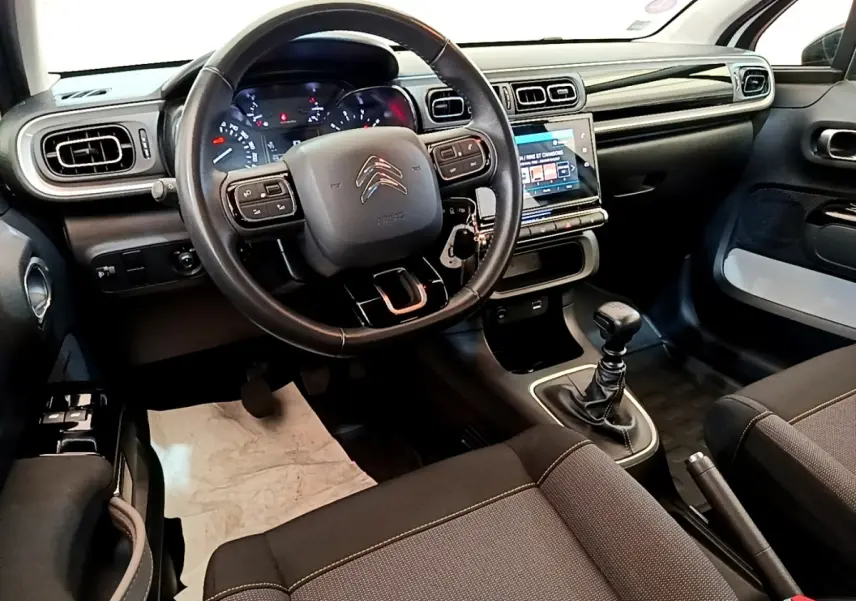 Vue intérieure avant de la Citroën C3 2021, volant cuir, tableau de bord avec écran tactile et boîte manuelle.