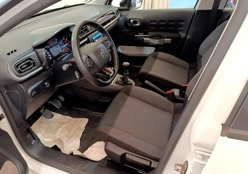 Intérieur de la Citroën C3 blanche, vue côté conducteur, avec tableau de bord noir et volant cuir multifonctions.
