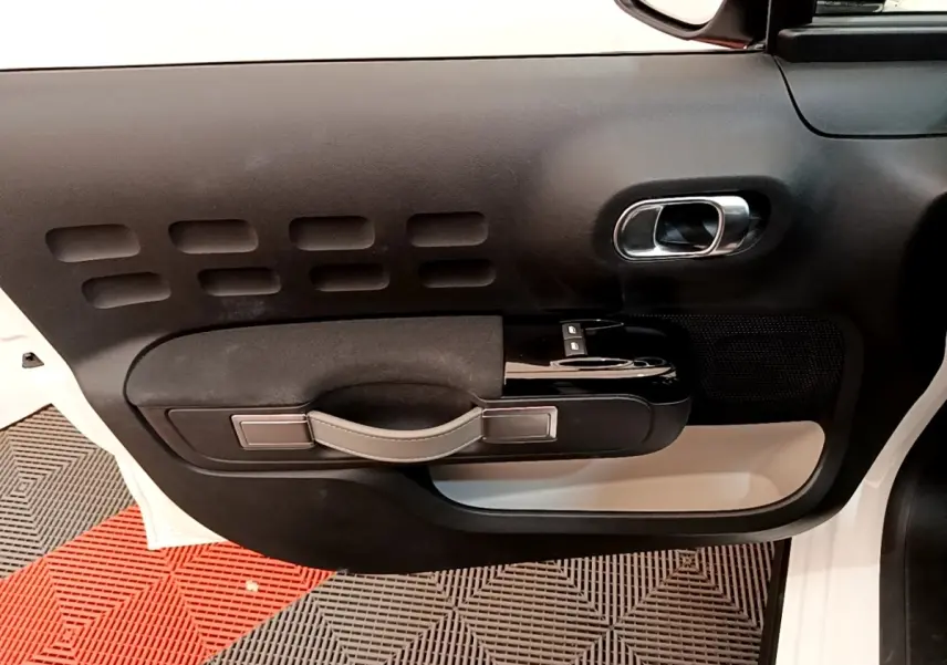 Vue intérieure de la porte avant gauche blanche d'une Citroën C3 2021 avec poignée noire et détails chromés.