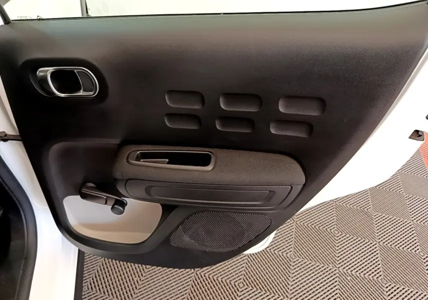 Vue rapprochée de la porte arrière gauche noire et blanche d'une Citroën C3 2021 avec poignée manuelle et haut-parleur intégré.