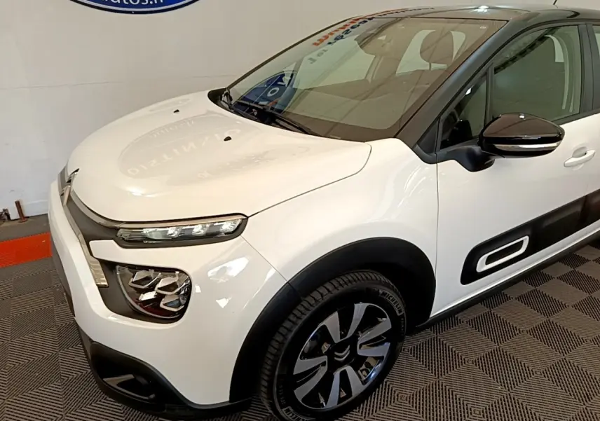 Vue 3/4 avant droite d'une Citroën C3 blanche avec protections latérales noires et jantes alliage distinctives.