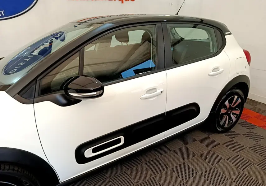 Vue latérale droite d'une Citroën C3 blanche 2021 avec protections noires sur les portes et rétroviseurs noirs.
