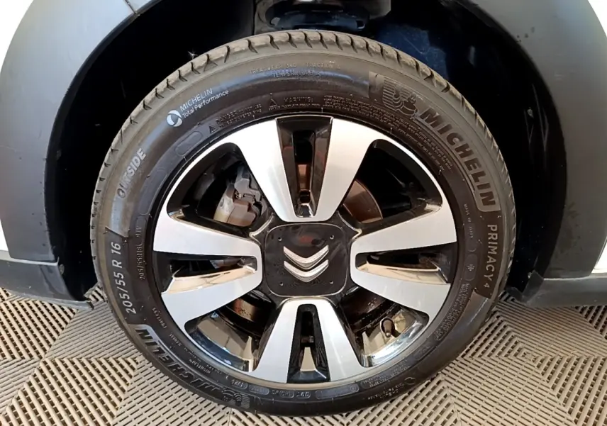 Gros plan sur la roue avant droite d’une Citroën C3 blanche, mettant en valeur la jante alliage bicolore et le pneu Michelin.