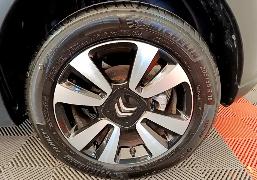 Gros plan sur la roue avant droite d'une Citroën C3 blanche, mettant en valeur la jante alliage et le pneu Michelin.