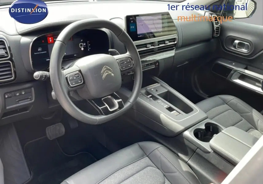 Vue intérieure côté conducteur du Citroën C5 Aircross Hybrid 136ch 2025, tableau de bord et volant multifonction noirs.