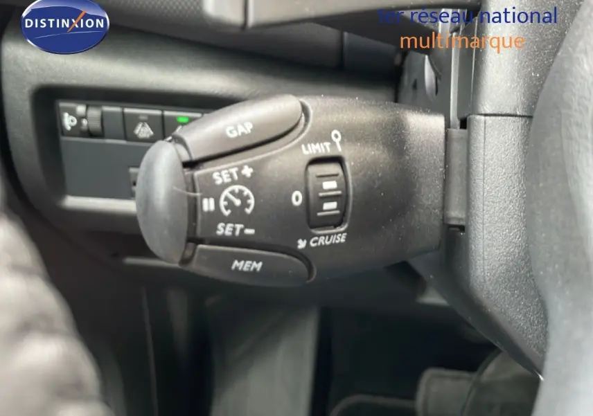 Gros plan sur la commande de régulateur de vitesse à gauche du volant dans l'habitacle du Citroën C5 Aircross gris platinium.