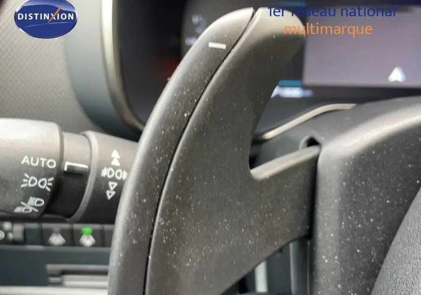 Gros plan sur la commande au volant noir du Citroën C5 Aircross Hybrid 2025, avec détails des commandes d'éclairage visibles.