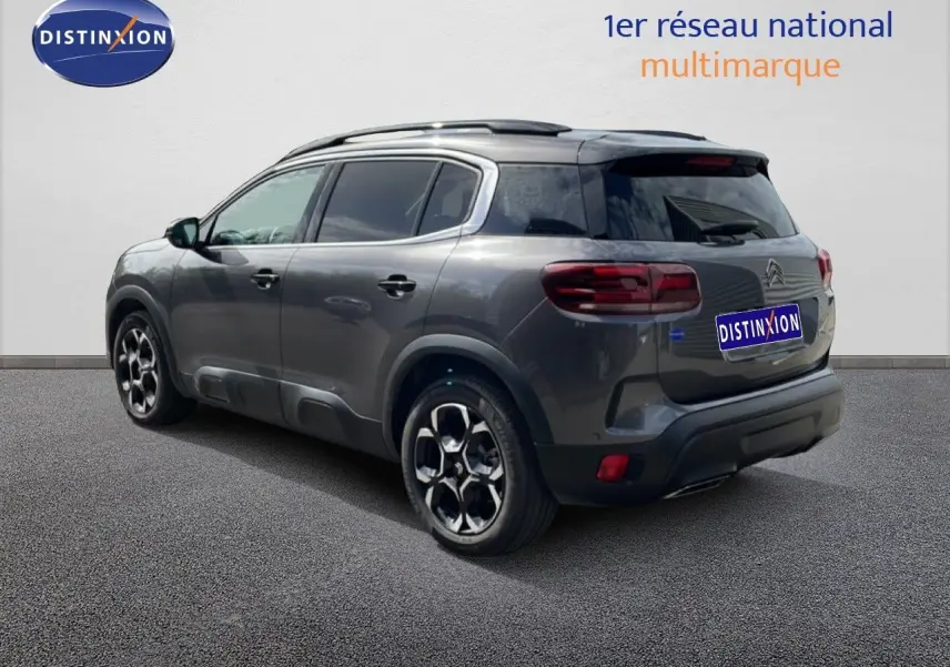 Vue 3/4 arrière droite d'un Citroën C5 Aircross Hybrid gris platinium métallisé avec jantes distinctives et toit noir.