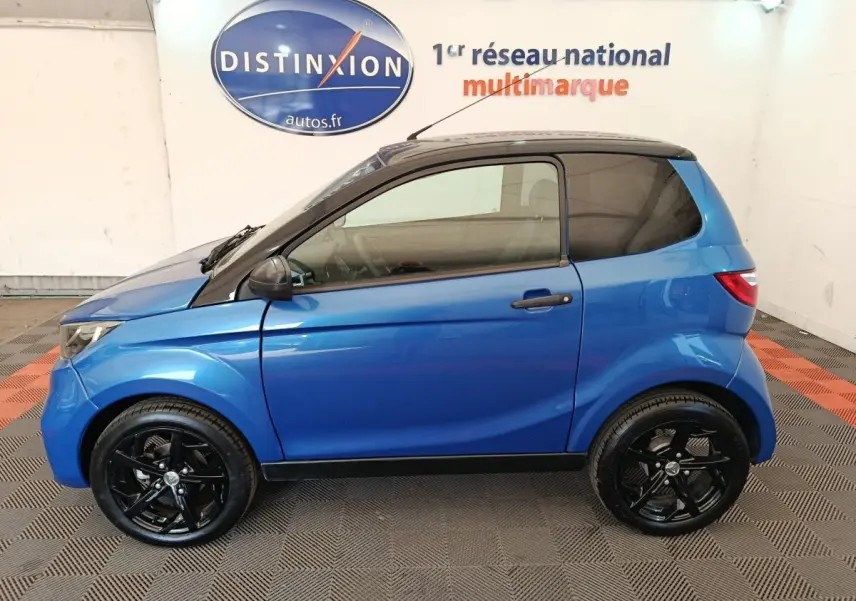 Vue de profil côté gauche d'une Aixam Ambition 0.5 City Sport 2024 bleu avec rétroviseur conducteur noir et jantes noires.
