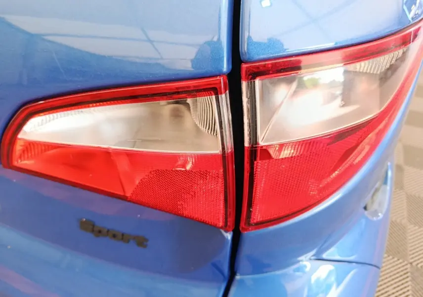 Gros plan sur les feux arrière gauche d'une Aixam Ambition 0.5 City Sport bleu 2024 avec logo Sport visible.
