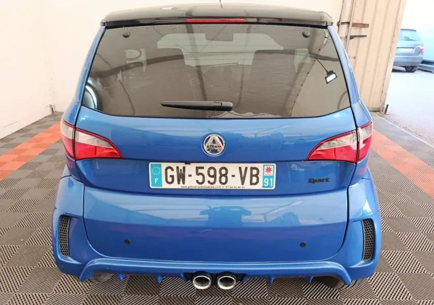 Vue arrière d'une Aixam Ambition 0.5 City Sport bleu 2024 avec double sortie d'échappement et logo Sport à droite.