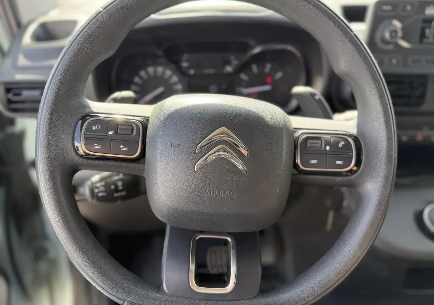 Vue rapprochée du volant noir du Citroën Berlingo FGN 1.5 HDi 130 2019 avec commandes intégrées et logo chromé central.