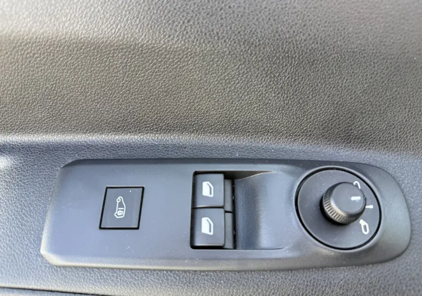 Gros plan sur les commandes de réglage des rétroviseurs et des vitres électriques côté conducteur du Citroën Berlingo beige.