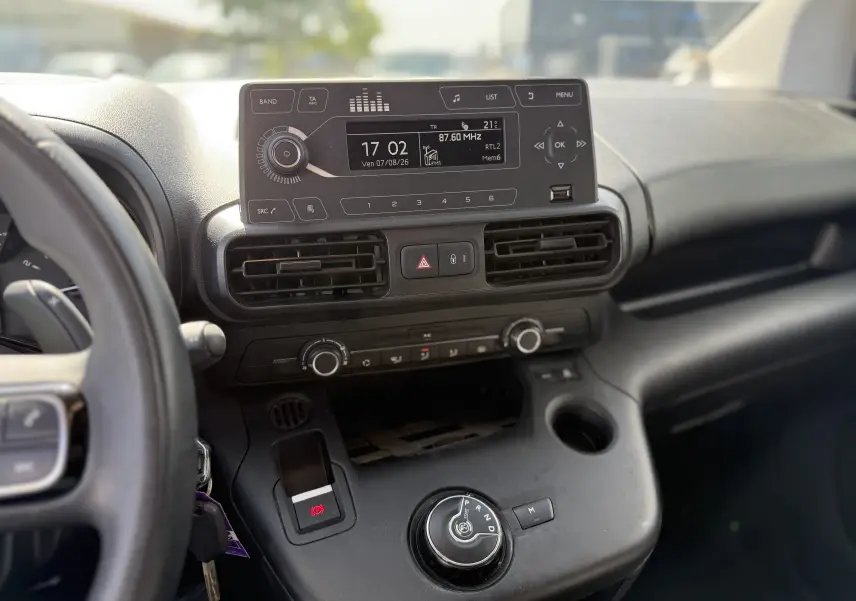 Vue intérieure du tableau de bord du Citroën Berlingo beige, avec écran central, commandes clim et boîte auto rotative.