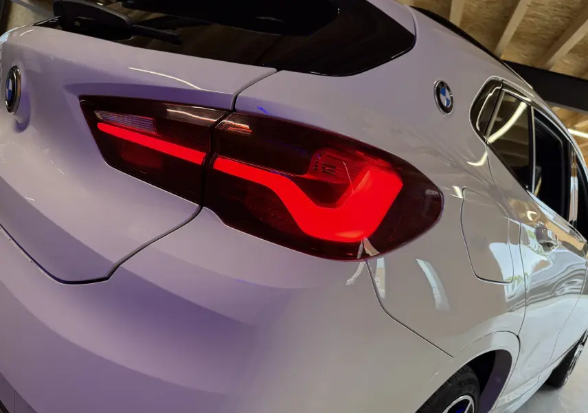 Feu arrière droit allumé d'une BMW X2 blanche vue en gros plan sur l'arrière et le côté droit.