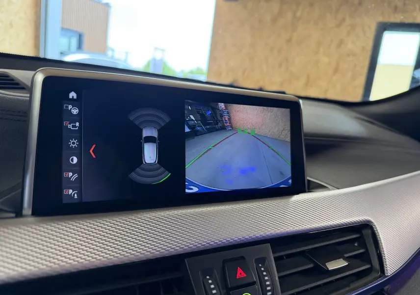Écran central de BMW X2 2023 montrant la caméra de recul avec guidage et capteurs de stationnement actifs.