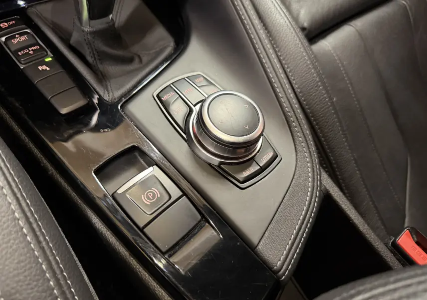 Gros plan sur la console centrale noire et les commandes de la boîte automatique du BMW X2 sDrive18d 2023.