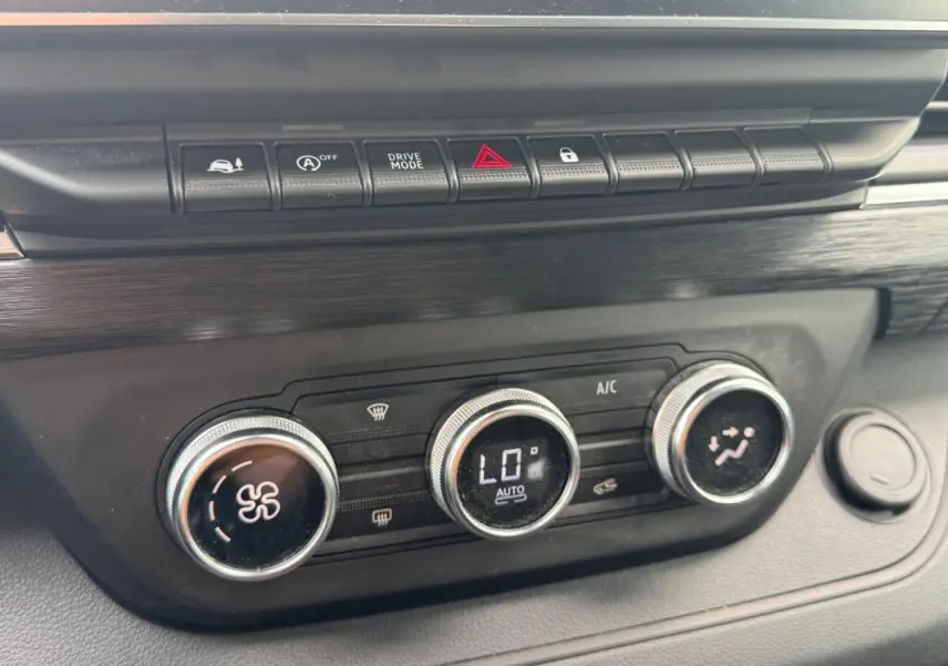Gros plan sur la console centrale du Renault Trafic Fourgon 2024, montrant les commandes de climatisation et les boutons de fonction.