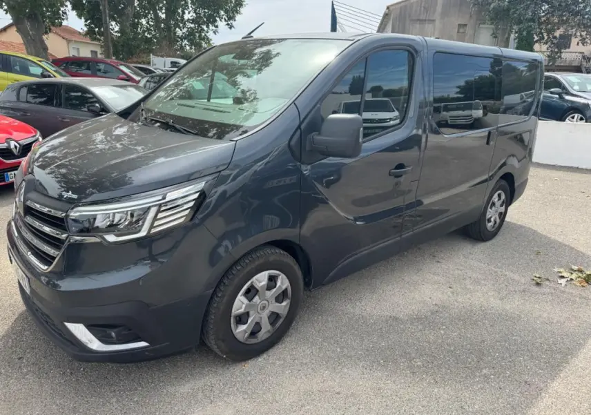 Renault Trafic Fourgon gris foncé vu en 3/4 avant droit avec vitres surteintées et porte latérale visible.