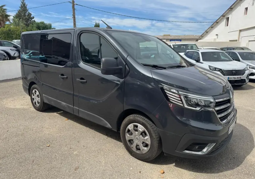 Renault Trafic Fourgon gris foncé vu en 3/4 avant droit avec vitres surteintées et porte latérale visible.