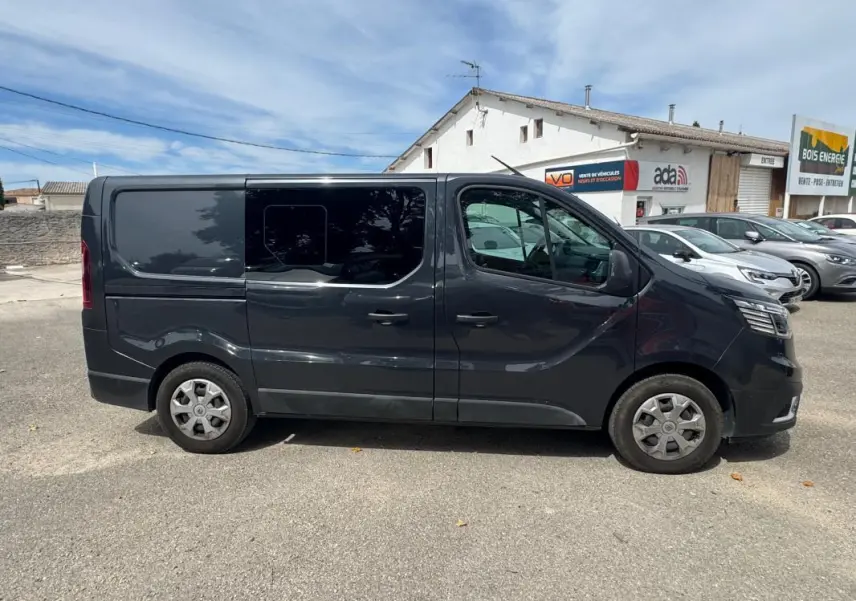 Vue de profil côté gauche d'un Renault Trafic Fourgon gris foncé avec vitres surteintées et porte latérale.