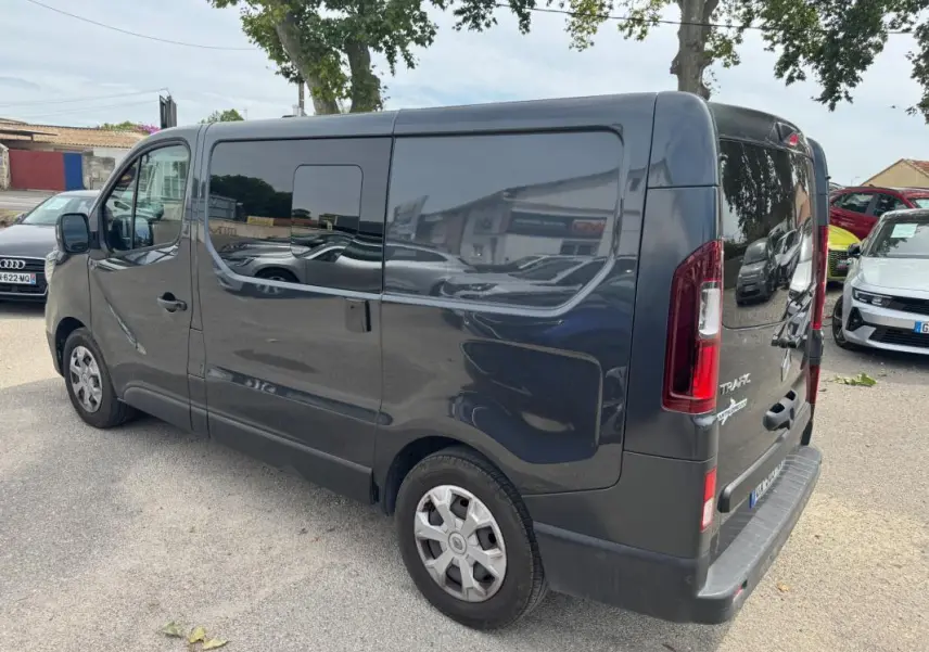 Vue 3/4 arrière droite d’un Renault Trafic Fourgon gris foncé avec porte latérale et vitres surteintées.