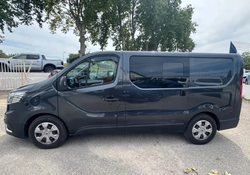 Profil côté gauche du Renault Trafic Fourgon gris foncé 2024 avec porte latérale et vitres surteintées.