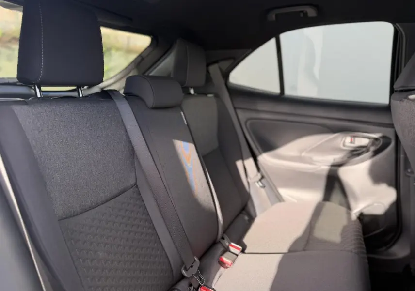Vue intérieure de la banquette arrière côté droit de la Toyota Yaris Cross 2026 avec sièges tissu gris et ceintures de sécurité.