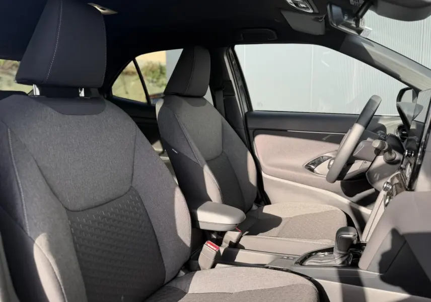 Vue intérieure côté droit montrant les sièges avant gris et le volant multifonctions du Toyota Yaris Cross 2026.