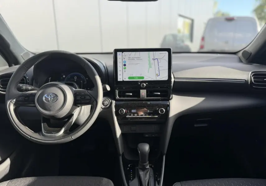 Vue intérieure avant du Toyota Yaris Cross 2026, tableau de bord noir avec écran tactile GPS et volant multifonctions cuir.