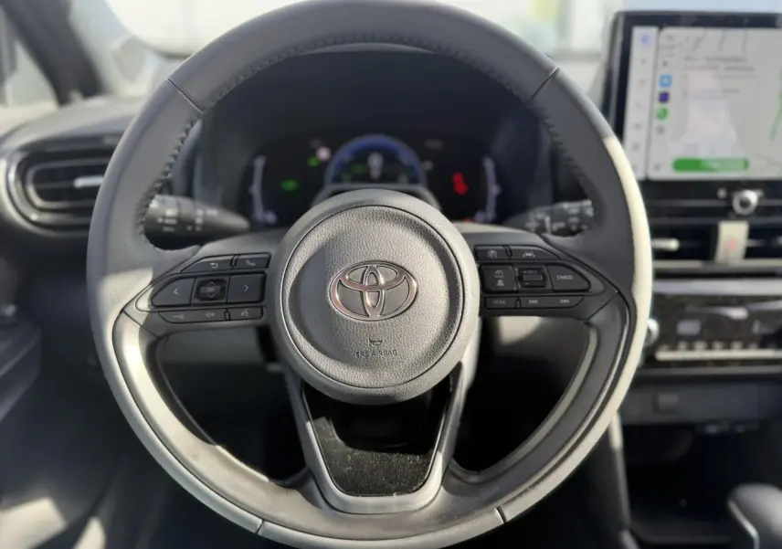 Vue rapprochée du volant en cuir multifonctions gris d’une Toyota Yaris Cross 2026 avec écran tactile et tableau de bord numérique.